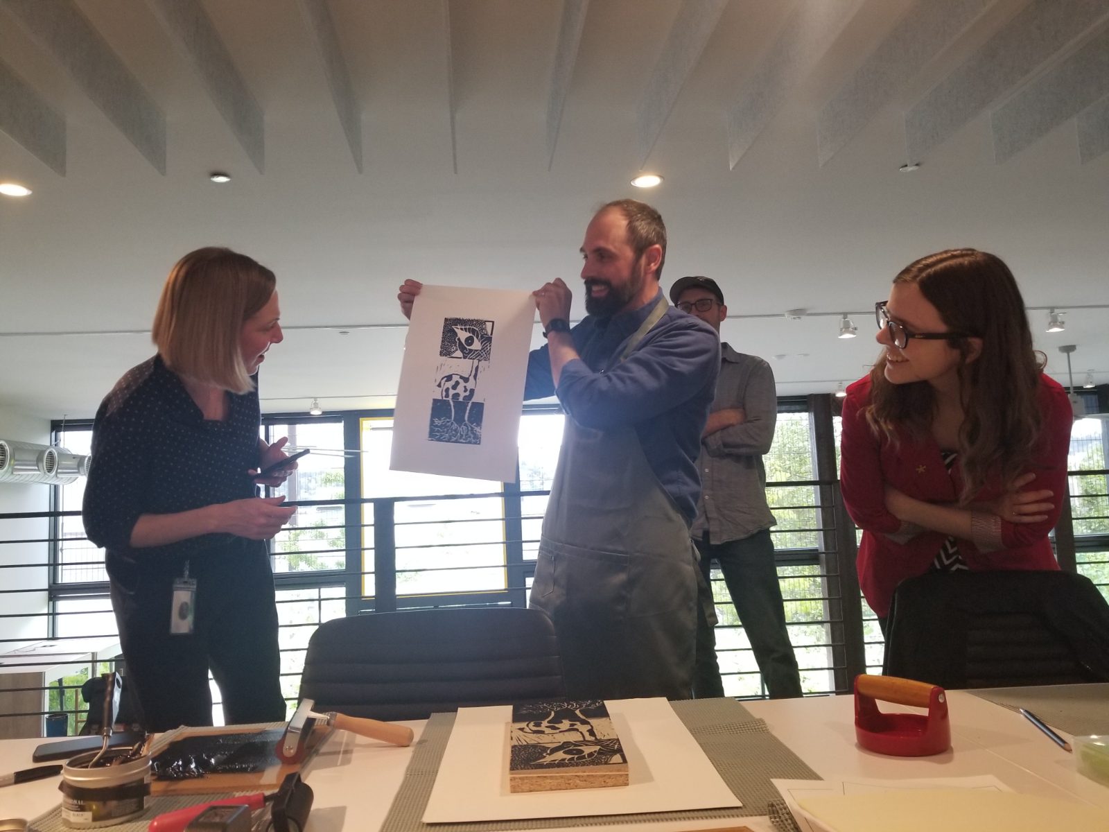 A colleague holding up a hand-pulled print at a spirit week workshop